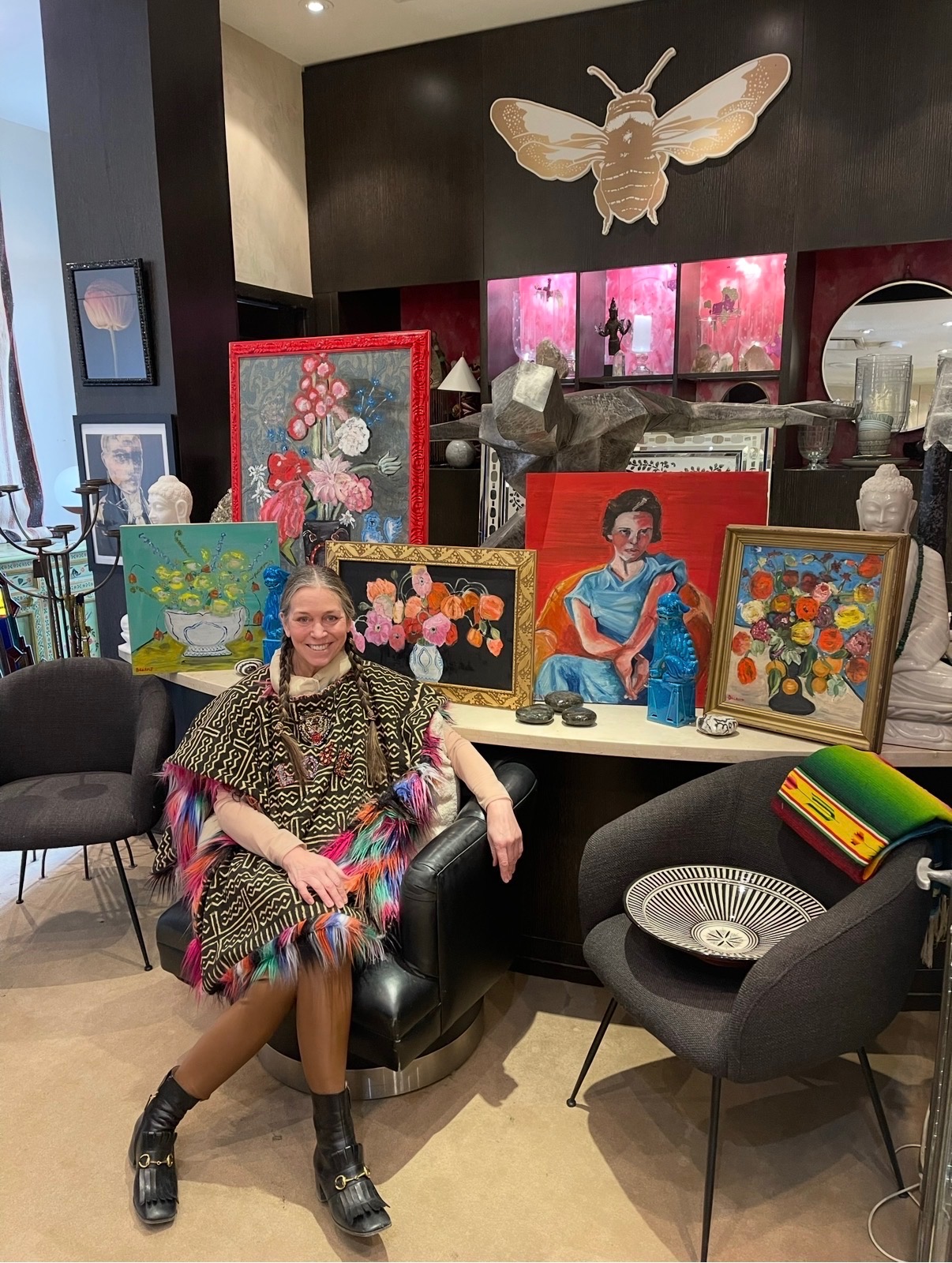 Annie Decamp seated among a display of her paintings