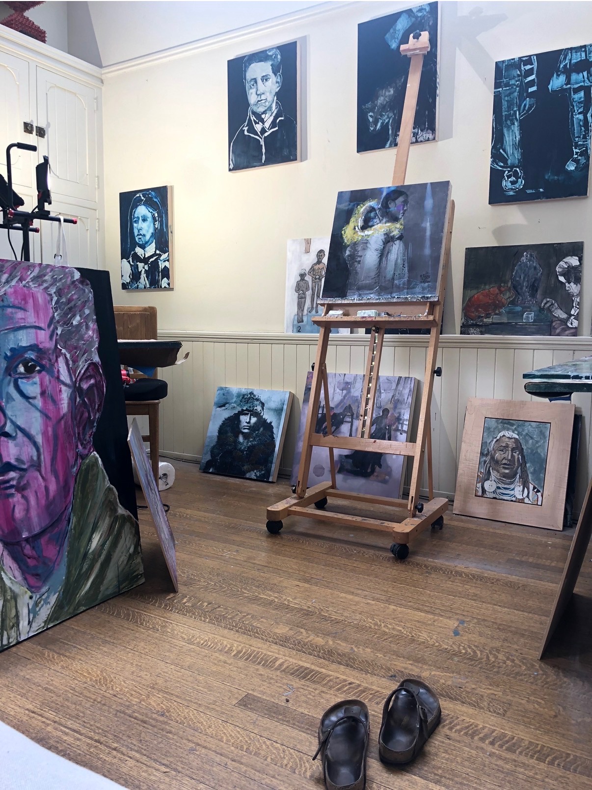 Annie Decamp's studio, wide view with canvases leaning against the wall and work on the easel.
